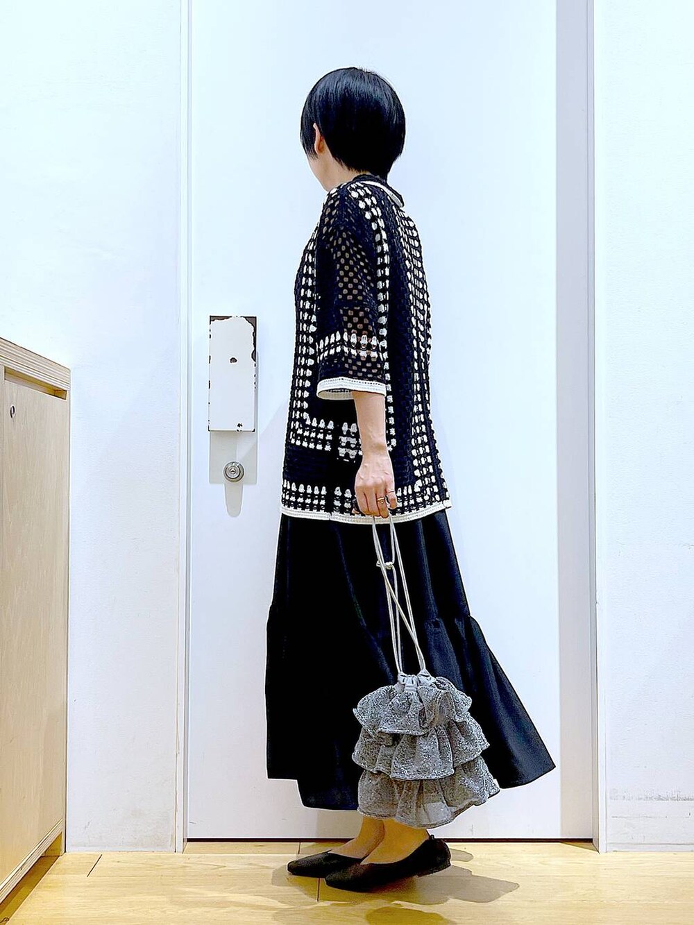 シルバー系のショルダーバッグ、ブラック系のパンプス、ブラック系のワンピースを着用したレディースの春コーディネートの3枚目の写真