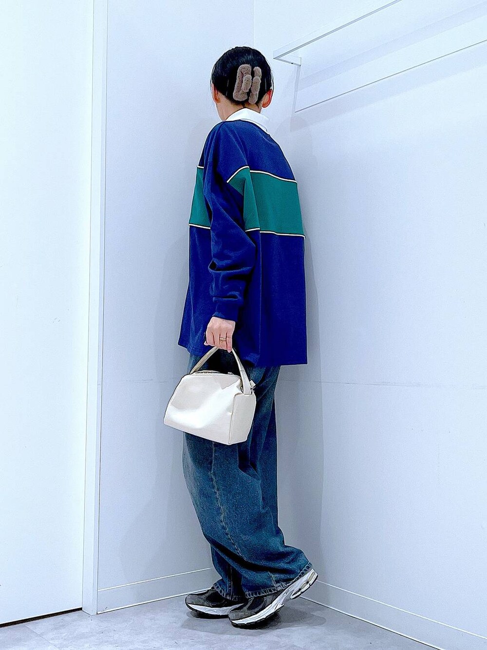 ブルー系のデニムパンツ、ホワイト系のショルダーバッグ、ブルー系のポロシャツを着用したレディースの冬コーディネートの3枚目の写真