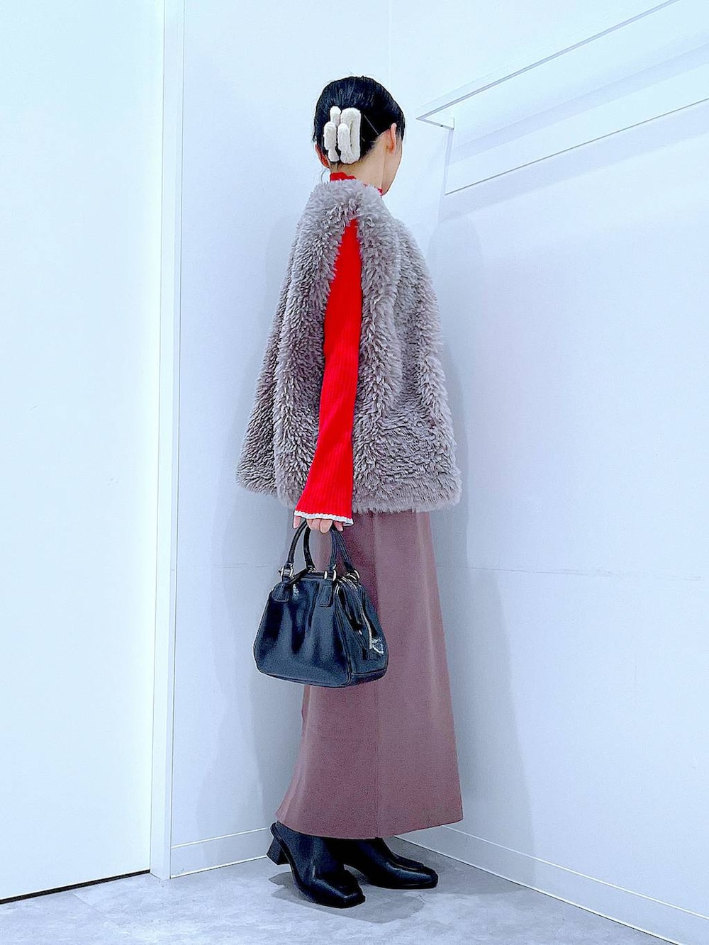 グレー系のベスト、レッド系のニット/セーター、ブラック系のブーツを着用したレディースの冬コーディネートの4枚目の写真