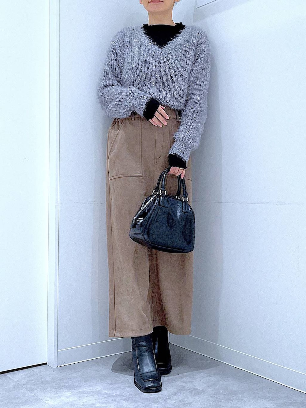 ブラック系のブーツ、ブラック系のショルダーバッグ、ブラウン系のスカートを着用したレディースの冬コーディネートの6枚目の写真