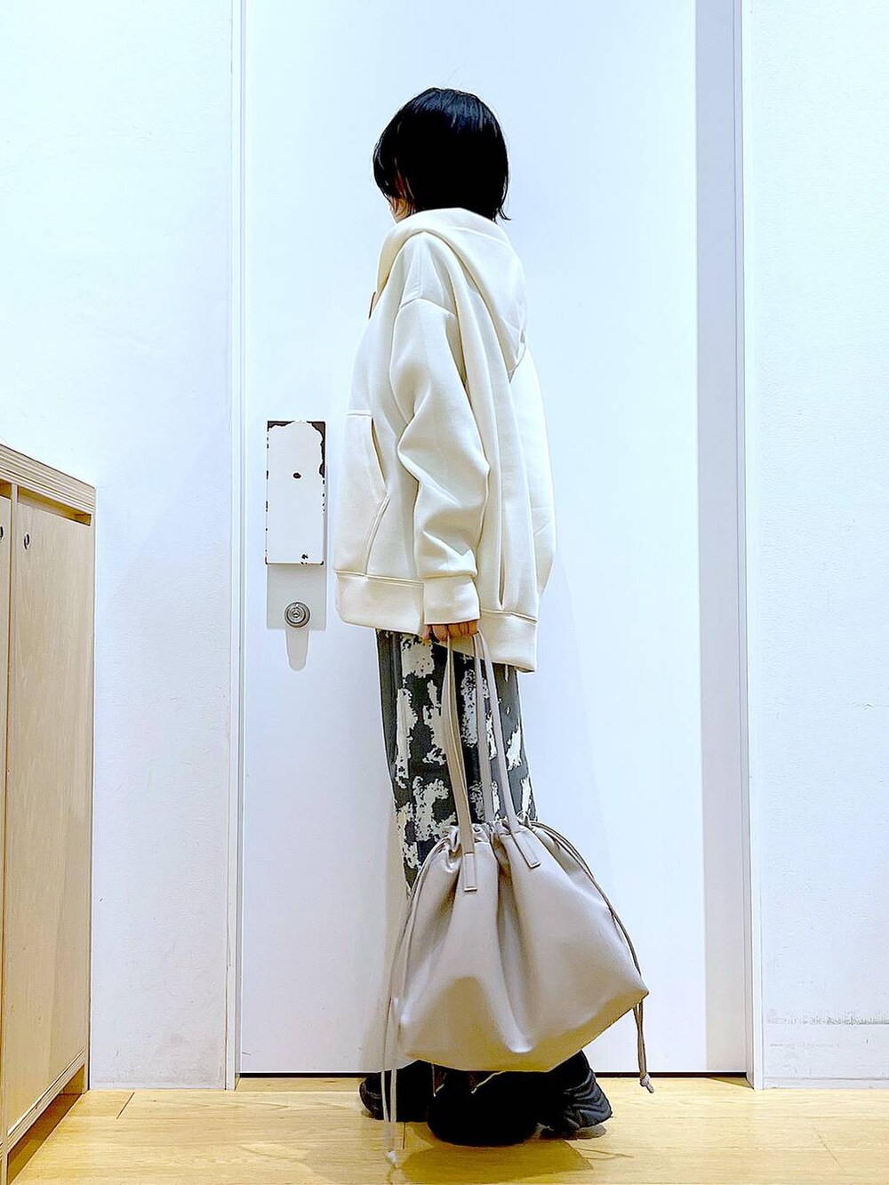 グレー系のスカート、ベージュ系のトートバッグ、ブラック系のブーツを着用したレディースの秋コーディネートの3枚目の写真