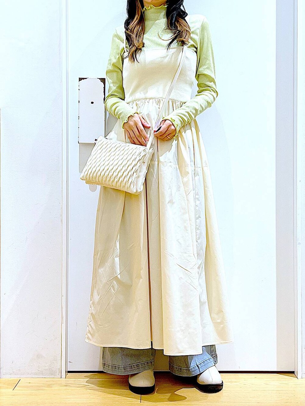 ホワイト系のショルダーバッグ、ベージュ系のブーツ、ブルー系のデニムパンツを着用したレディースの冬コーディネートの6枚目の写真