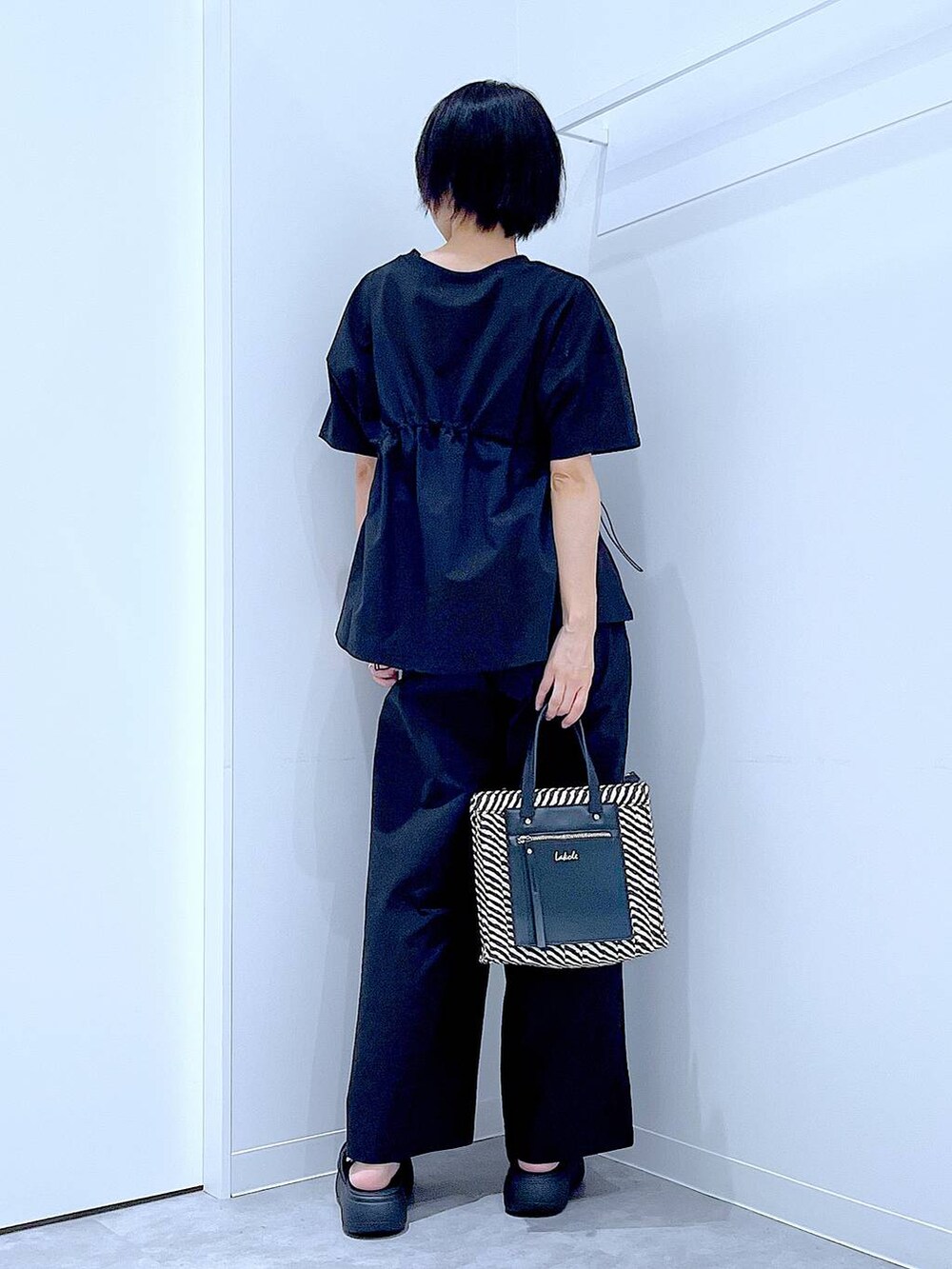 ブラック系のショルダーバッグ、ブラック系のサンダル、ブラック系のTシャツ/カットソーを着用したレディースの夏コーディネートの5枚目の写真