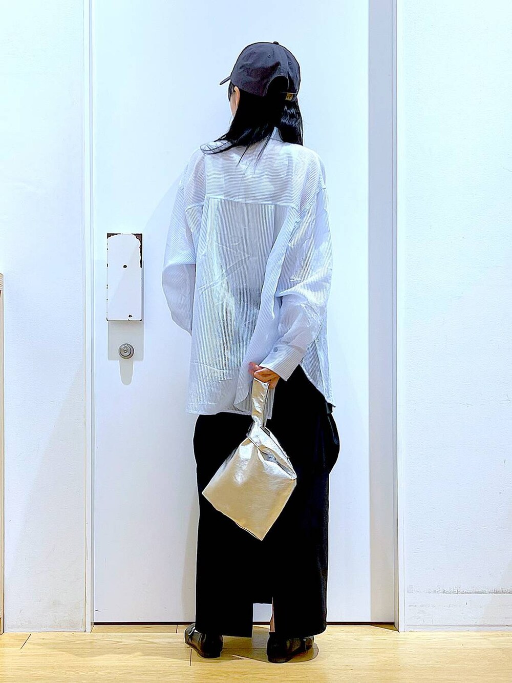 シルバー系のショルダーバッグ、ブラック系のパンプス、ブラック系のスカートを着用したレディースの春コーディネートの5枚目の写真