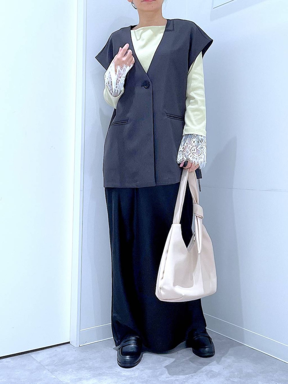 ブラック系のスカート、グレー系のベスト、ブラック系のローファーを着用したレディースの春コーディネートの6枚目の写真