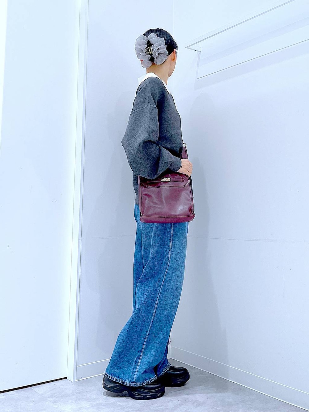 ブルー系のデニムパンツ、レッド系のショルダーバッグ、グレー系のニット/セーターを着用したレディースの秋コーディネートの4枚目の写真