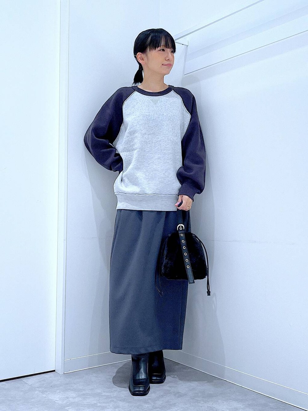 グレー系のスカート、グレー系のニット/セーター、ブラック系のブーツを着用したレディースの秋コーディネートの2枚目の写真