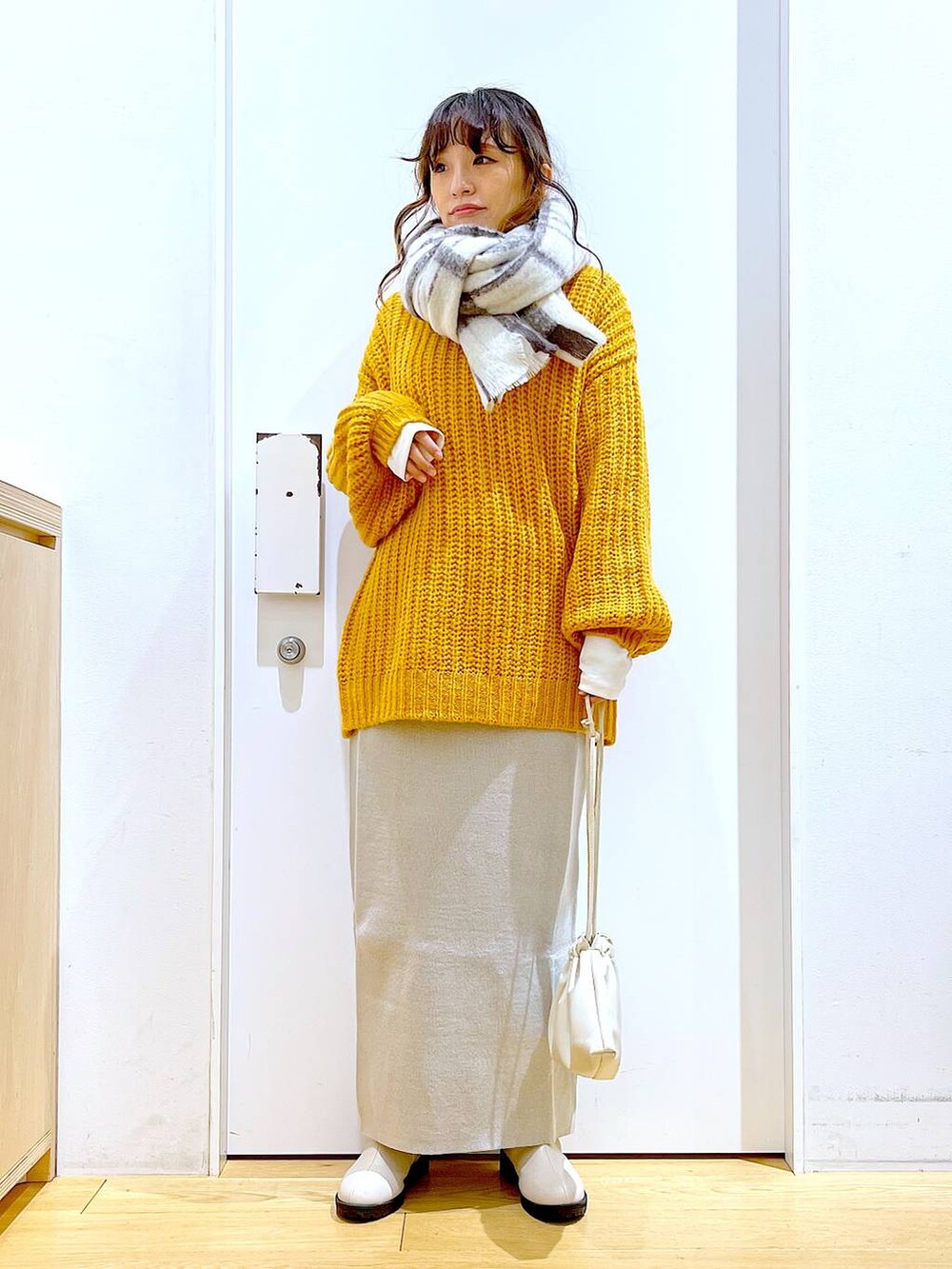 グレー系のスカート、ベージュ系のブーツ、ベージュ系のショルダーバッグを着用したレディースの冬コーディネートの2枚目の写真