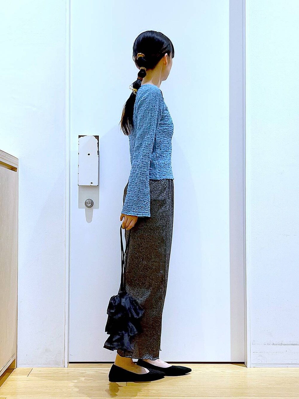 ブラック系のスカート、ブラック系のショルダーバッグ、ブラック系のパンプスを着用したレディースの春コーディネートの4枚目の写真