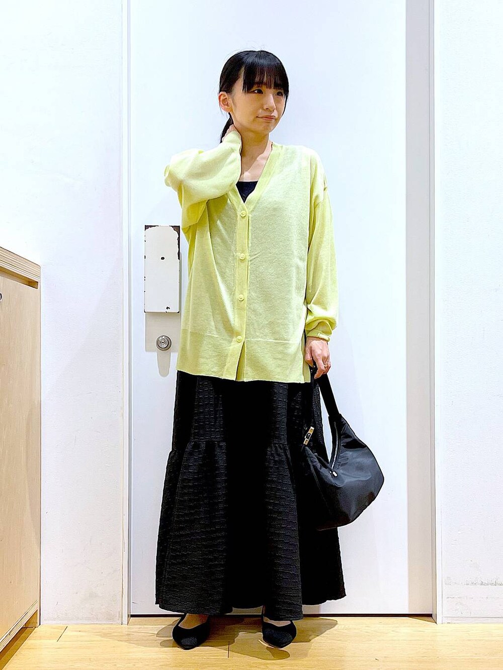 ブラック系のワンピース、グリーン系のカーディガン/ボレロ、ブラック系のショルダーバッグを着用したレディースの春コーディネートの2枚目の写真