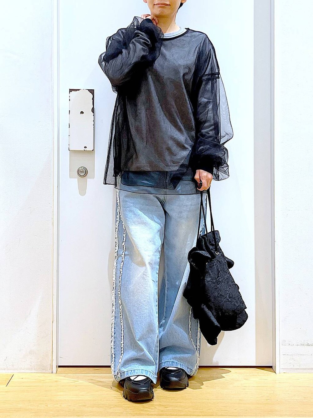 ブラック系のスニーカー、ブラック系のショルダーバッグ、ブルー系のデニムパンツを着用したレディースの春コーディネートの6枚目の写真