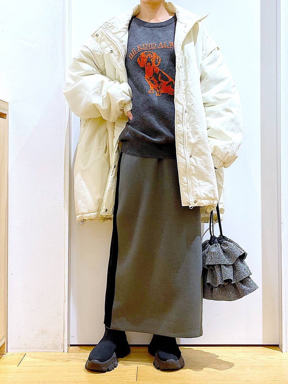 グレー系のスカート、ブラック系のブーツ、ホワイト系のその他アウターを着用したレディースの冬コーディネートの6枚目の写真