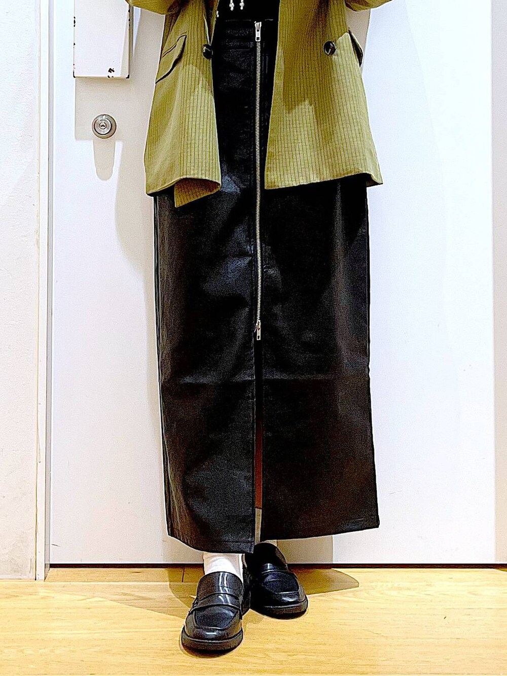 ホワイト系のベスト、ブラック系のスカート、ブラック系のショルダーバッグを着用したレディースの秋コーディネートの8枚目の写真