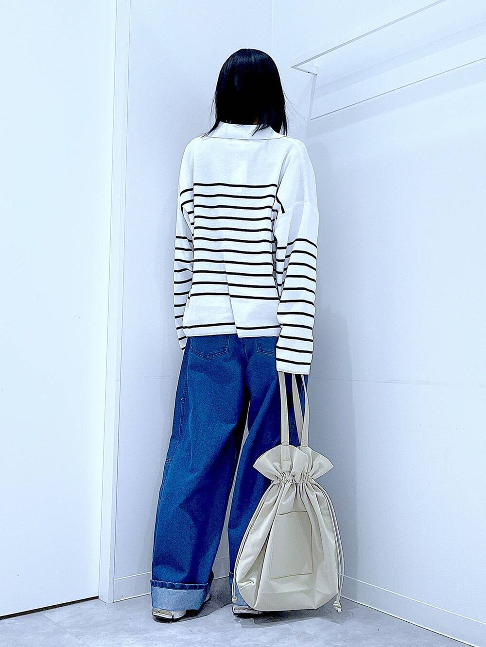 ブラック系のTシャツ/カットソー、ベージュ系のトートバッグ、ブルー系のデニムパンツを着用したレディースの冬コーディネートの5枚目の写真