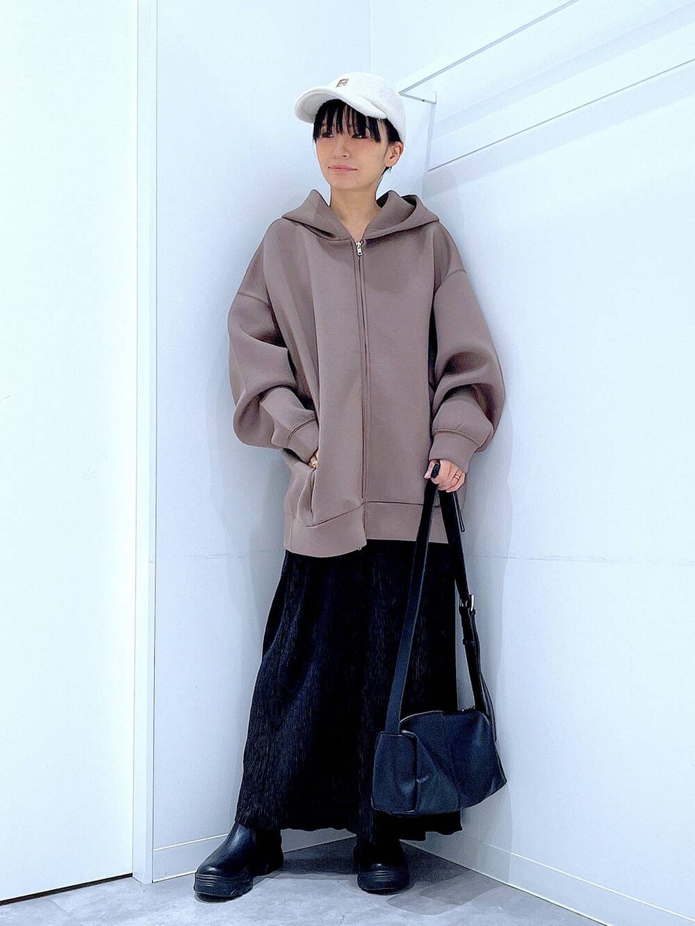 ブラック系のショルダーバッグ、ブラック系のブーツ、ブラウン系のパーカーを着用したレディースの秋コーディネートの2枚目の写真