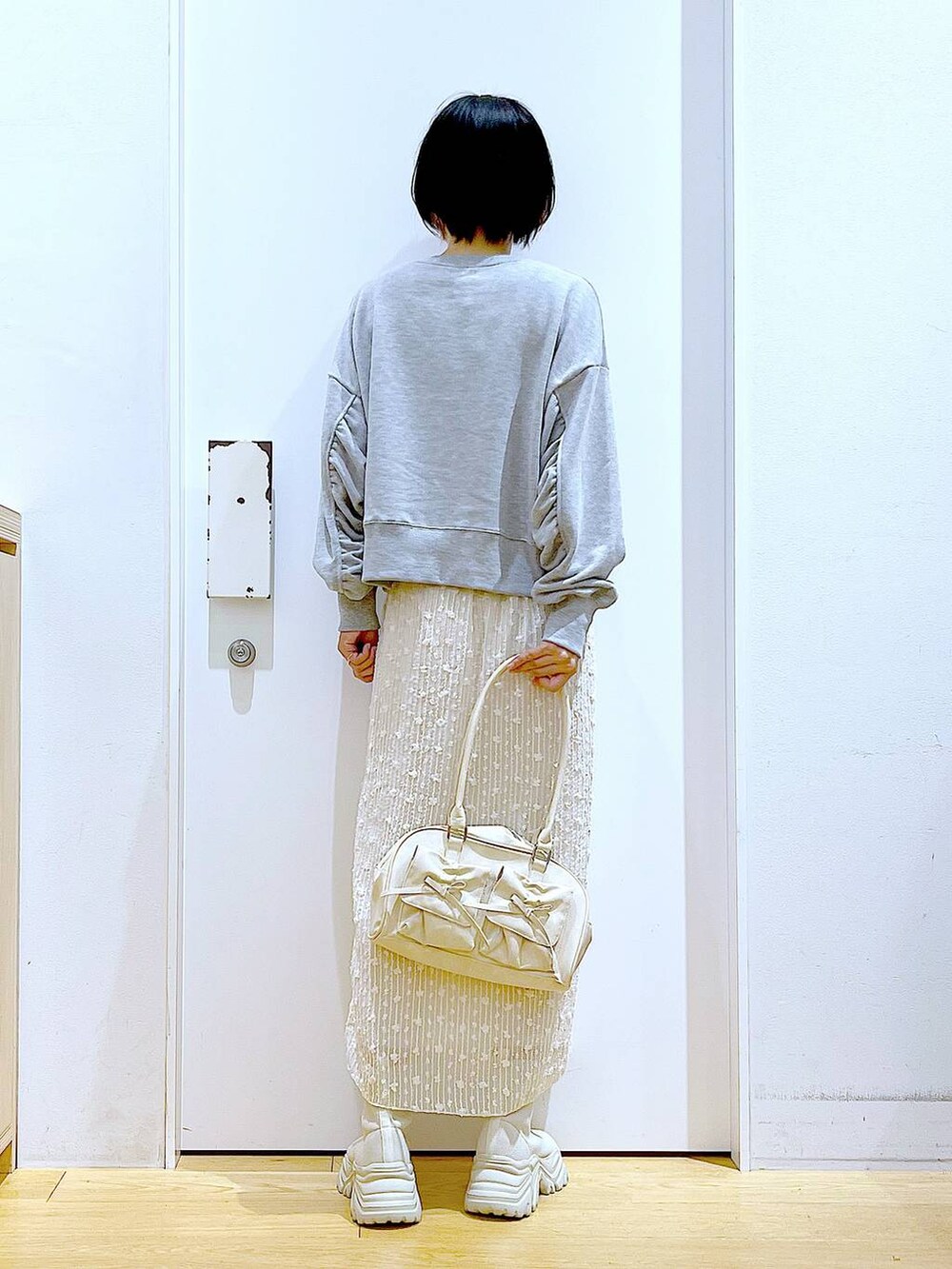 ホワイト系のハンドバッグ、グレー系のスウェット、ベージュ系のブーツを着用したレディースの秋コーディネートの5枚目の写真