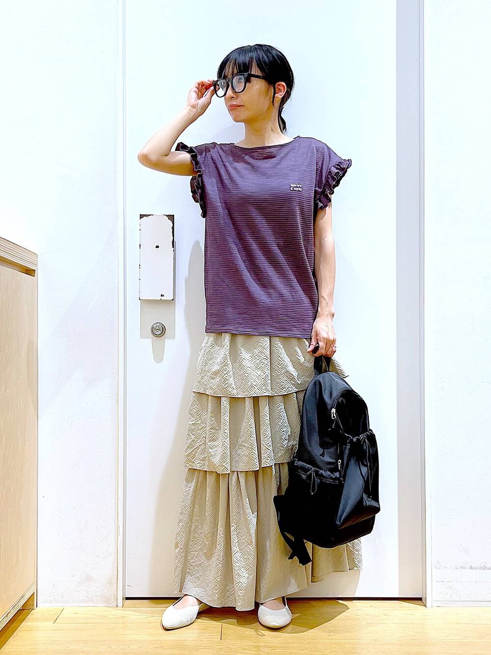 ブラウン系のTシャツ/カットソー、ベージュ系のスカート、ブラック系のバックパック/リュックを着用したレディースの春コーディネートの2枚目の写真