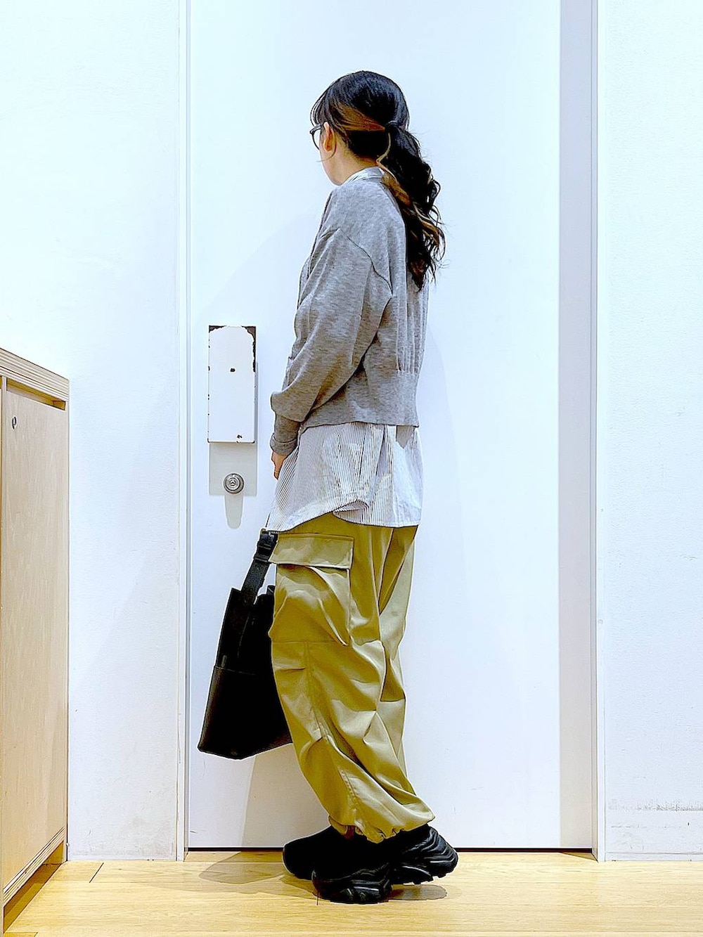 ブラック系のショルダーバッグ、グレー系のカーディガン/ボレロ、ブラック系のスニーカーを着用したレディースの春コーディネートの3枚目の写真