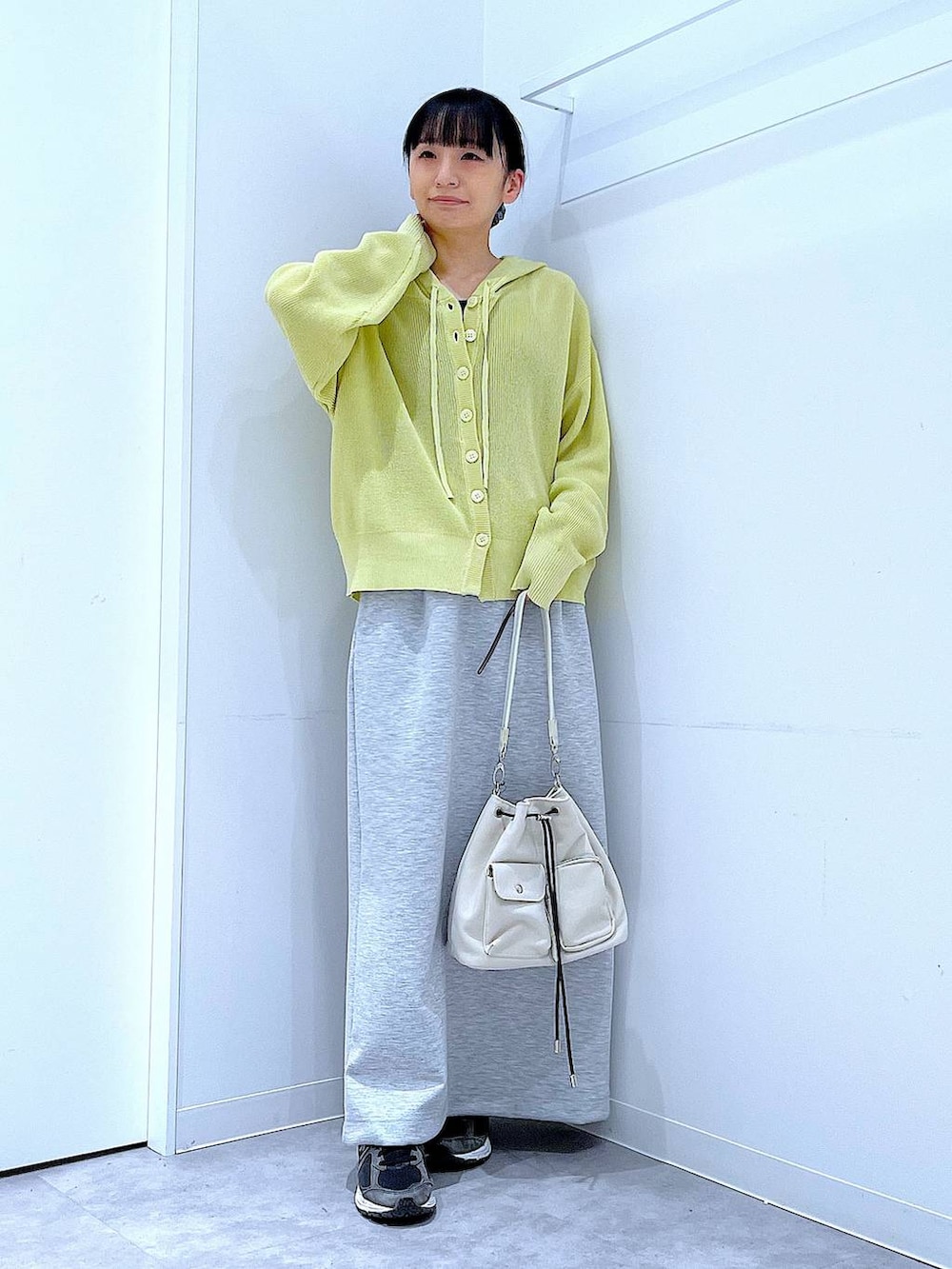 ベージュ系のショルダーバッグ、グレー系のスカート、イエロー系のカーディガン/ボレロを着用したレディースの春コーディネートの2枚目の写真