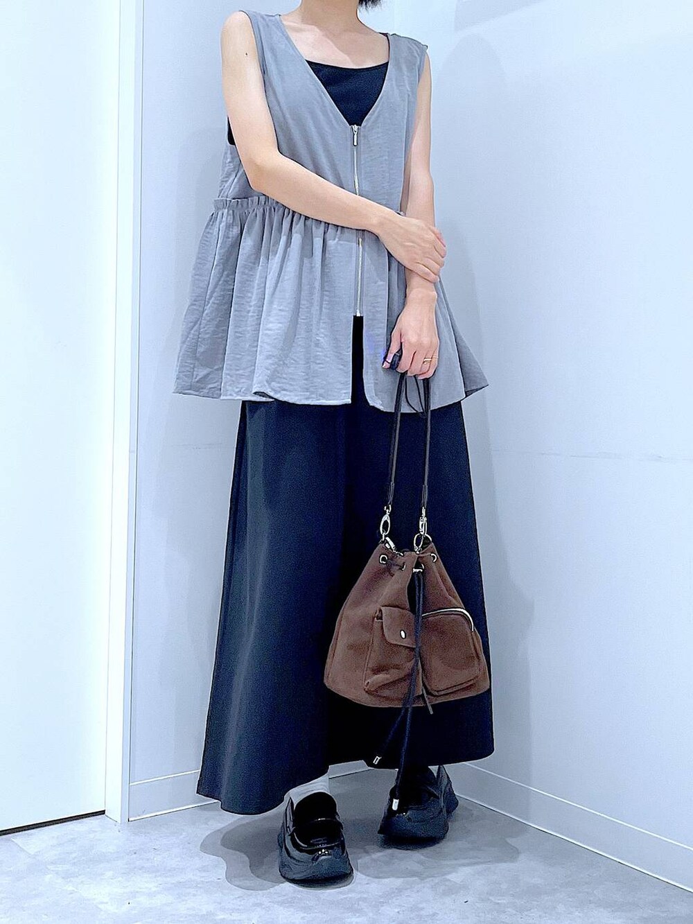 ブラック系のスカート、ブラック系のローファー、ブラウン系のショルダーバッグを着用したレディースの秋コーディネートの6枚目の写真