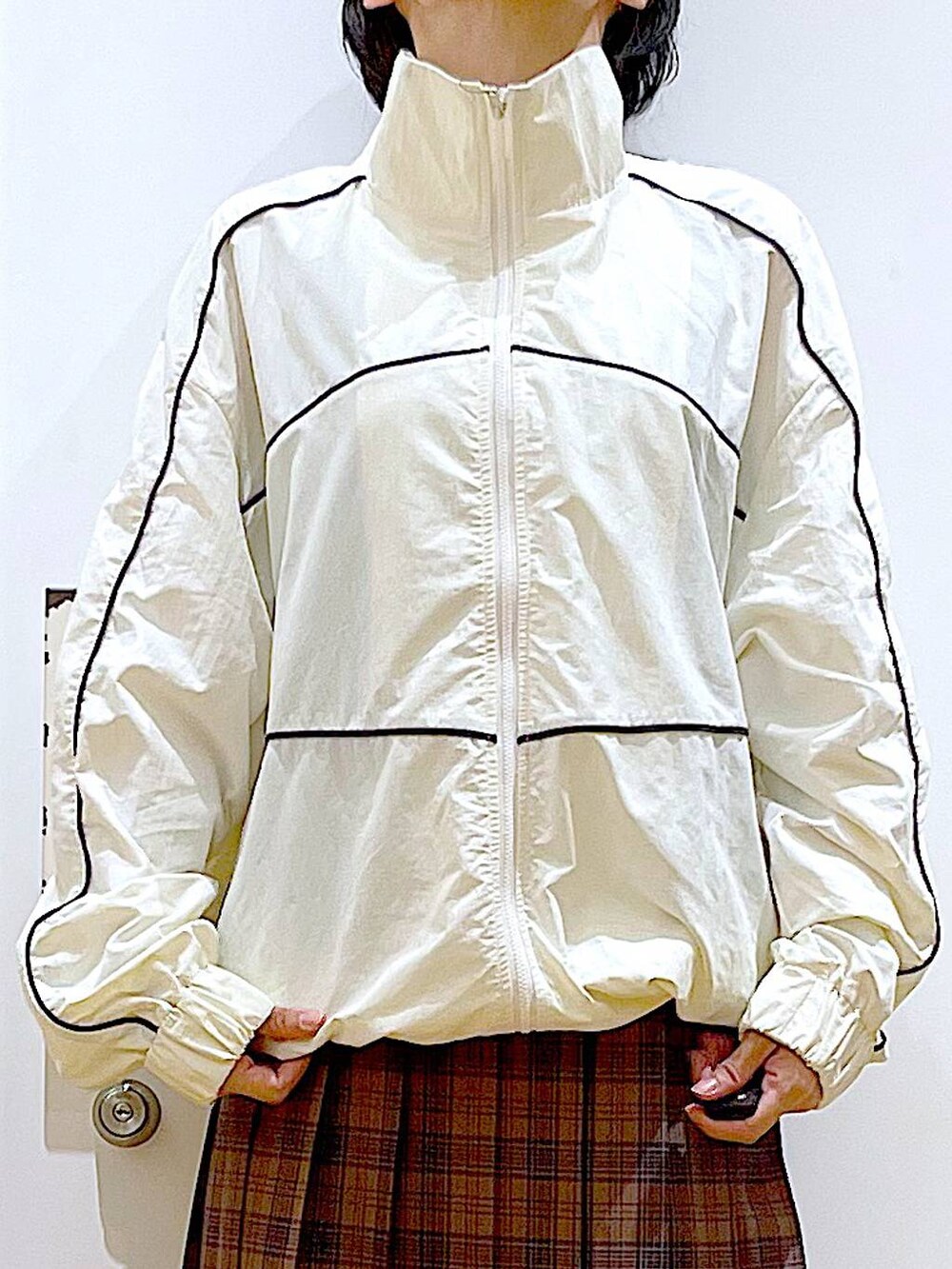 ホワイト系のショルダーバッグ、ベージュ系のブルゾン、ブラック系のブーツを着用したレディースの秋コーディネートの7枚目の写真