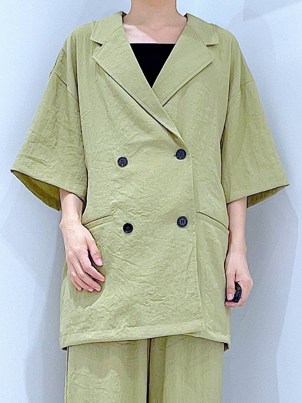 ホワイト系のショルダーバッグ、ブラック系のサンダル、グリーン系のテーラードジャケットを着用したレディースの夏コーディネートの7枚目の写真