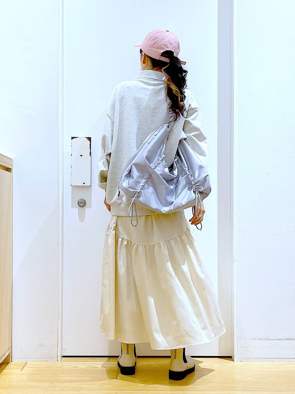 ベージュ系のスウェット、ホワイト系のスカート、ベージュ系のブーツを着用したレディースの春コーディネートの5枚目の写真