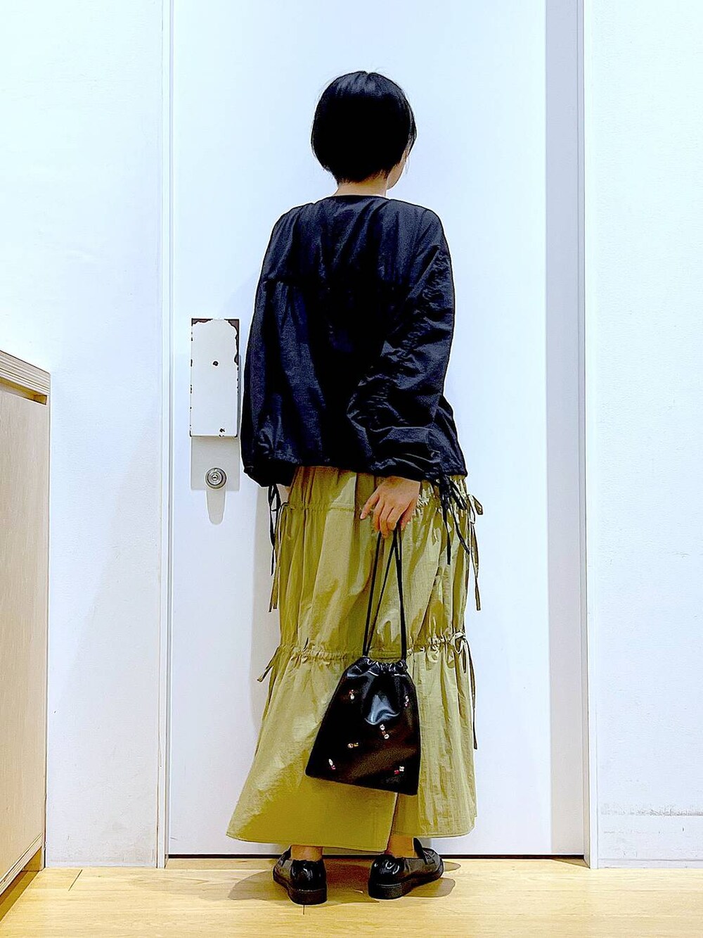 ブラック系のショルダーバッグ、ブラック系のローファー、イエロー系のスカートを着用したレディースの秋コーディネートの5枚目の写真