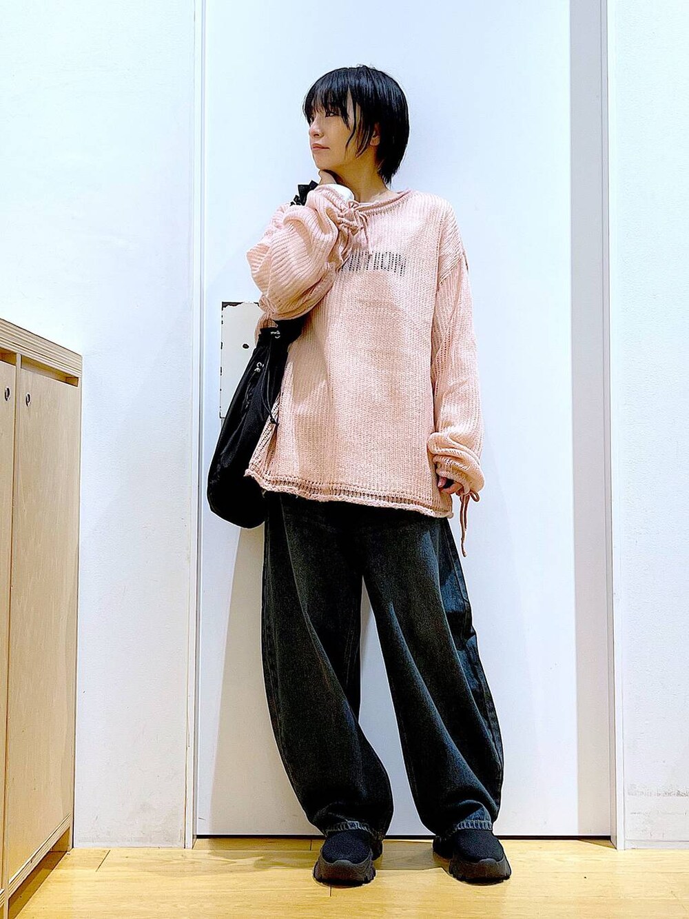 ブラック系のショルダーバッグ、ブラック系のブーツ、ピンク系のニット/セーターを着用したレディースの冬コーディネートの2枚目の写真