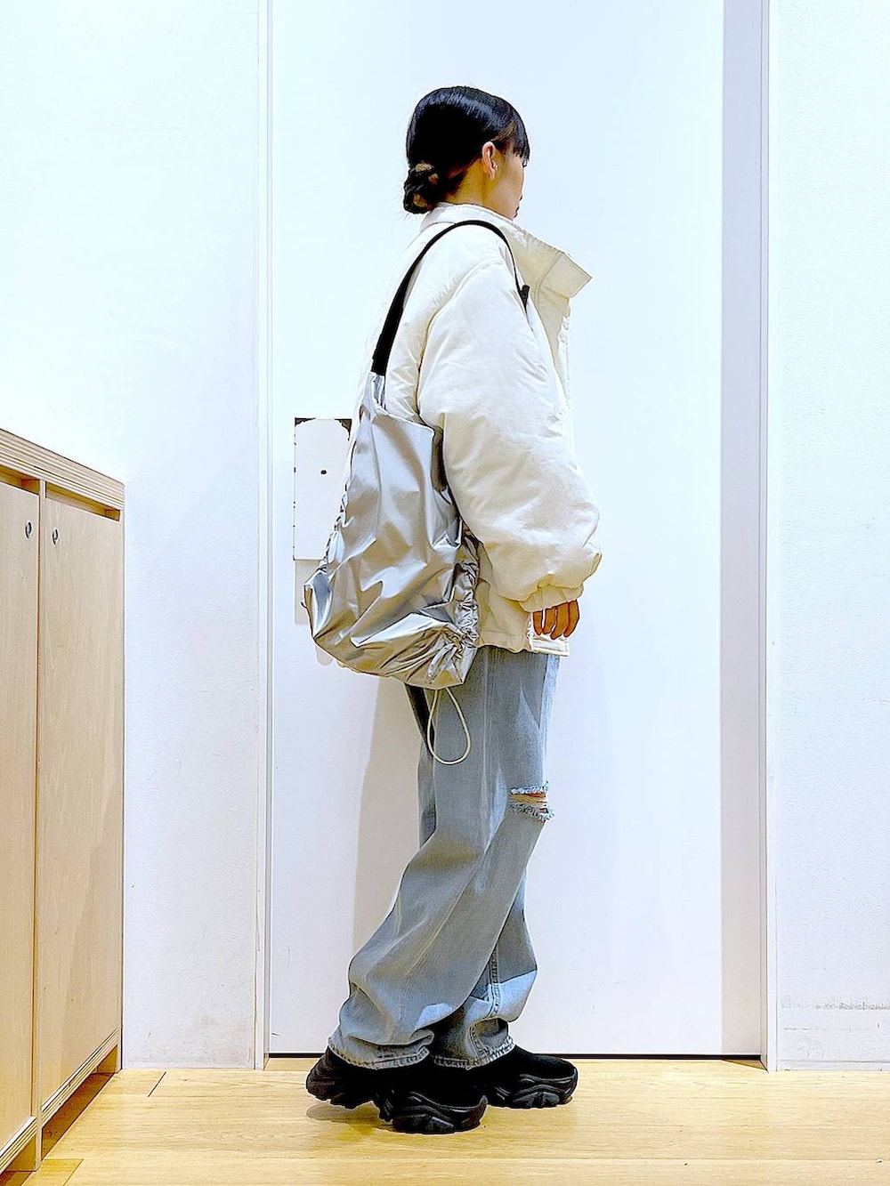 ブラック系のブーツ、ブルー系のデニムパンツ、シルバー系のショルダーバッグを着用したレディースの冬コーディネートの4枚目の写真