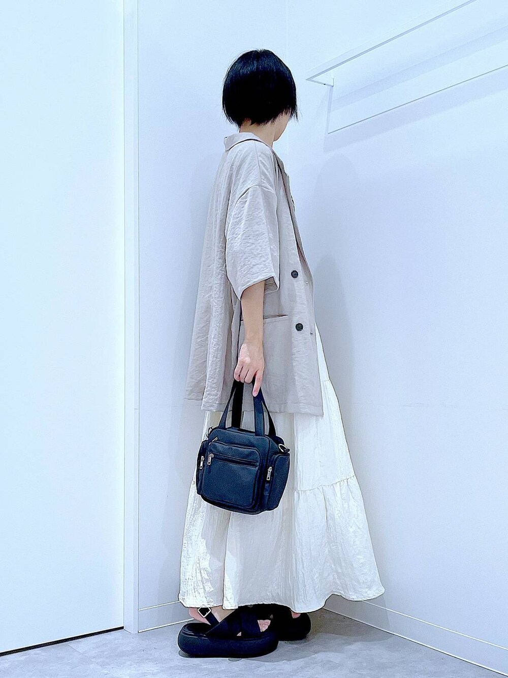 ブラック系のサンダル、ベージュ系のテーラードジャケット、ブラック系のショルダーバッグを着用したレディースの夏コーディネートの4枚目の写真