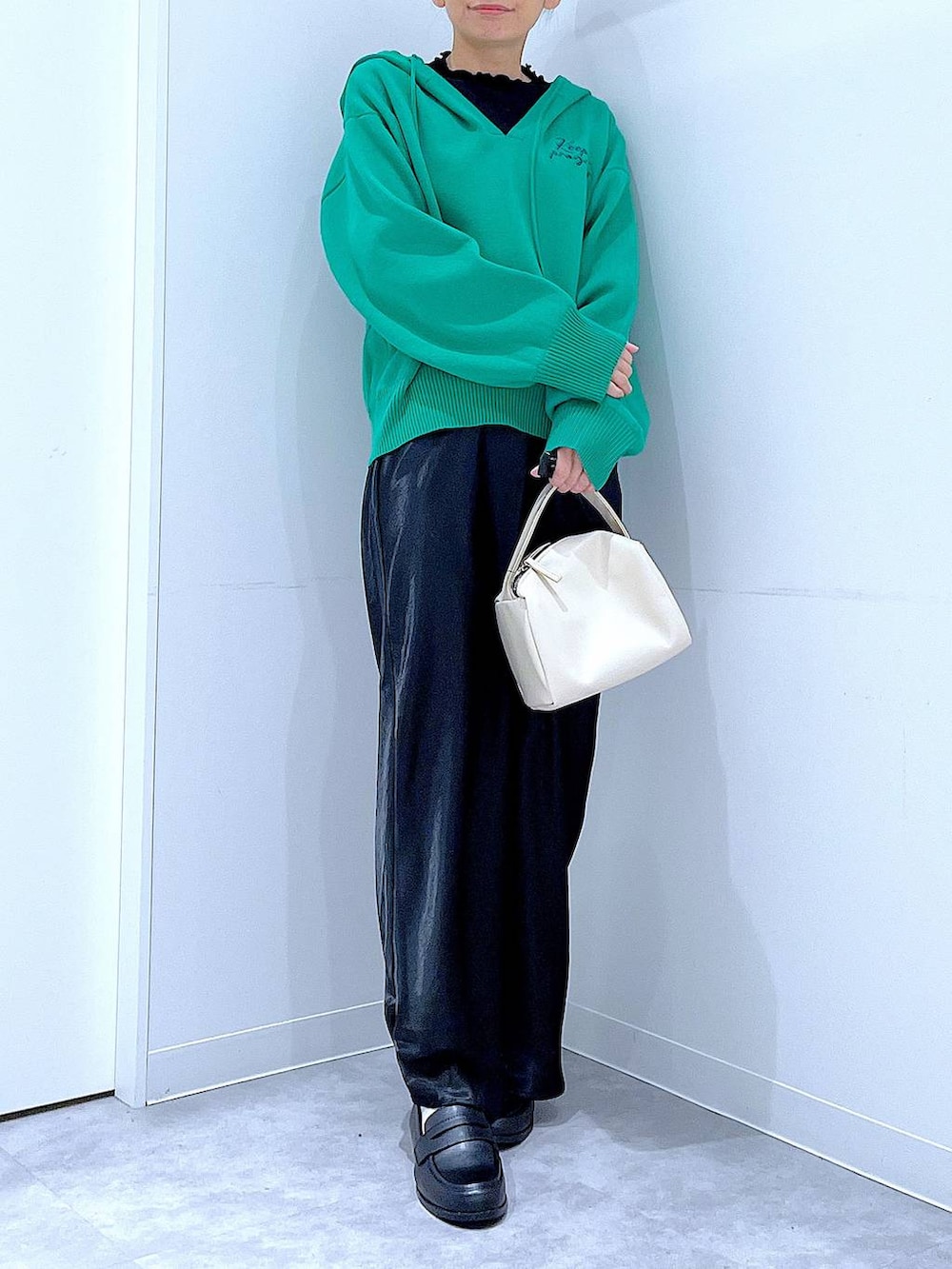 ブラック系のTシャツ/カットソー、ホワイト系のショルダーバッグ、グリーン系のニット/セーターを着用したレディースの春コーディネートの6枚目の写真