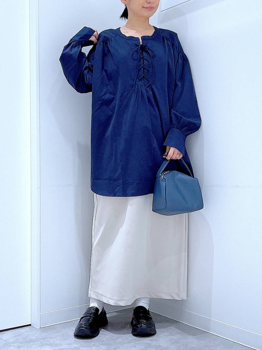 ベージュ系のスカート、ブラック系のローファー、ブルー系のショルダーバッグを着用したレディースの秋コーディネートの6枚目の写真