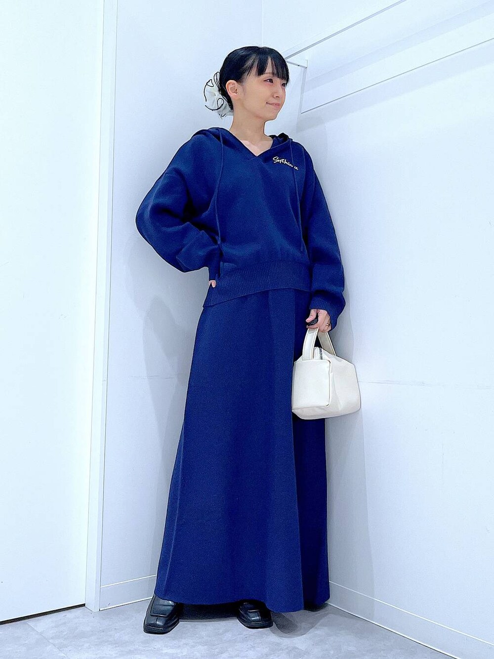 ブラック系のブーツ、ホワイト系のショルダーバッグ、ブルー系のスカートを着用したレディースの冬コーディネートの2枚目の写真