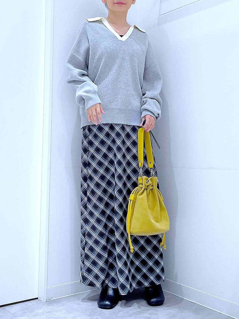ブラック系のブーツ、ブラック系のスカート、イエロー系のショルダーバッグを着用したレディースの秋コーディネートの6枚目の写真