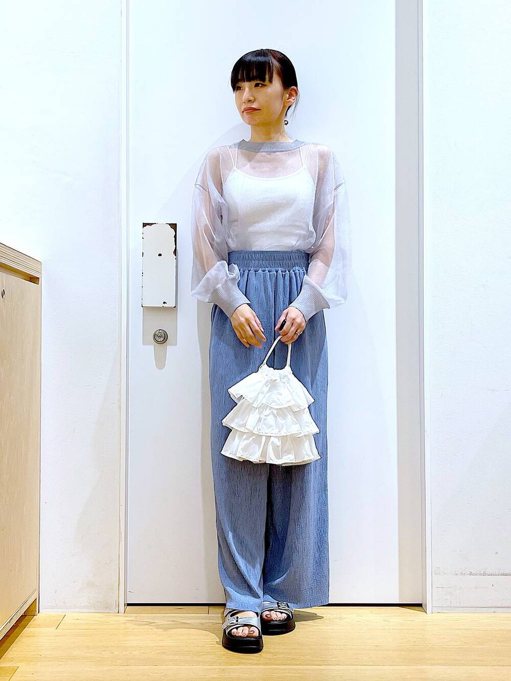 ホワイト系のショルダーバッグ、シルバー系のサンダル、グレー系のカーディガン/ボレロを着用したレディースの春コーディネートの2枚目の写真