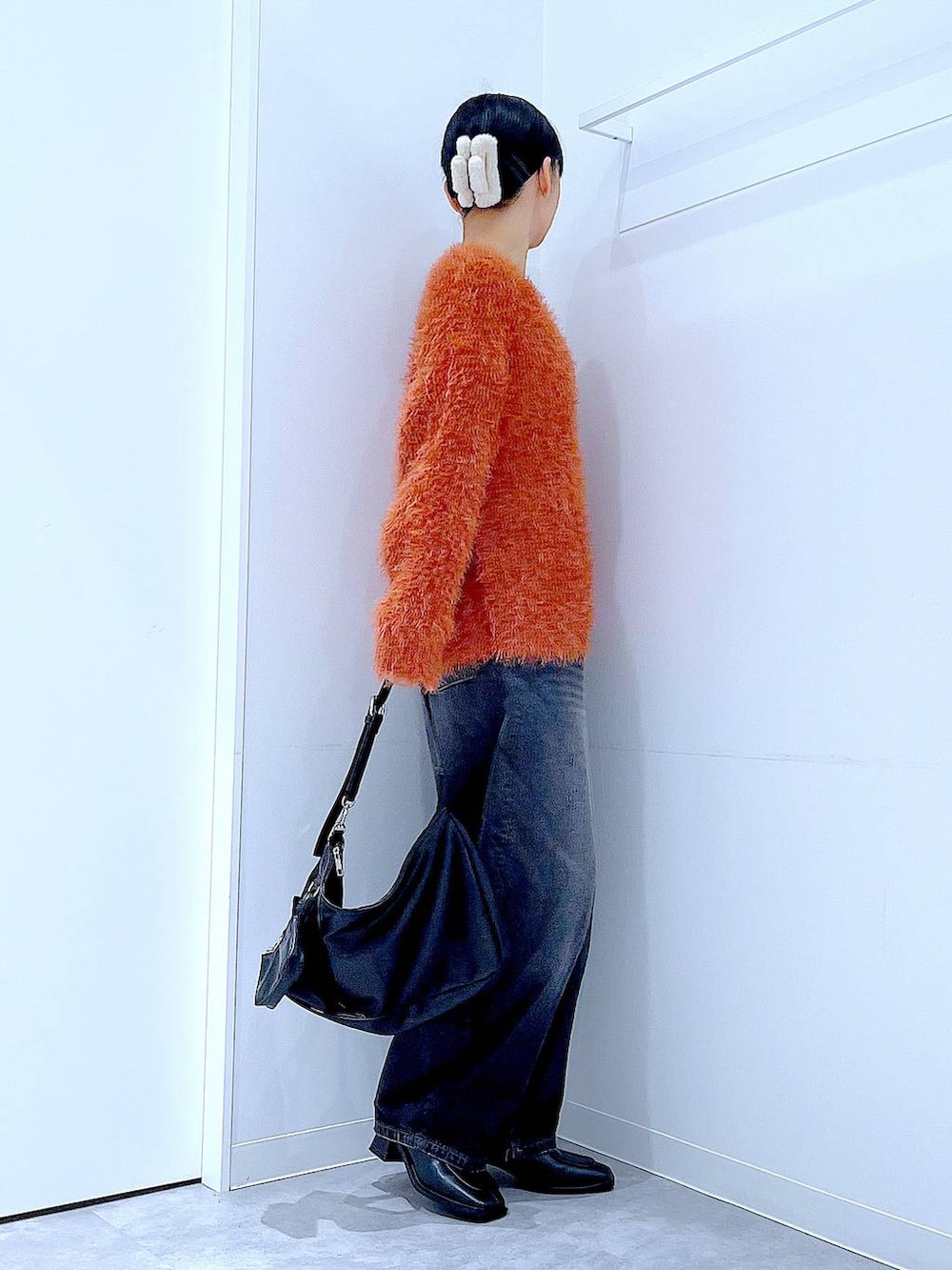 ブラック系のデニムパンツ、ブラック系のブーツ、ブラック系のショルダーバッグを着用したレディースの秋コーディネートの4枚目の写真