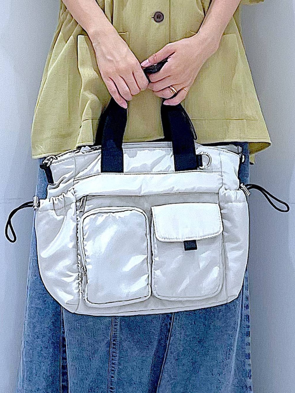 ホワイト系のトートバッグ、ホワイト系のサンダル、イエロー系のシャツ/ブラウスを着用したレディースの夏コーディネートの9枚目の写真