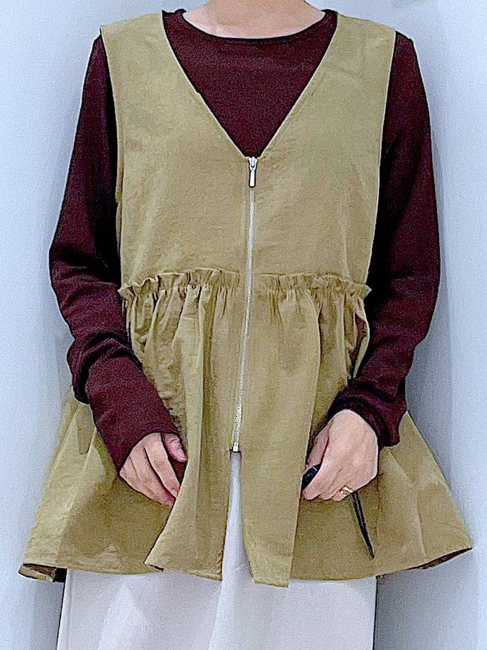 イエロー系のベスト、グレー系のスカート、ブラウン系のTシャツ/カットソーを着用したレディースの秋コーディネートの7枚目の写真