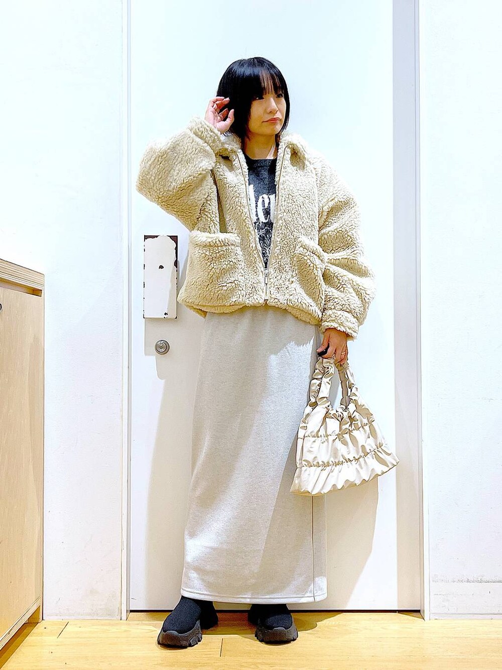ホワイト系のブルゾン、ブラック系のブーツ、ベージュ系のスカートを着用したレディースの冬コーディネートの2枚目の写真