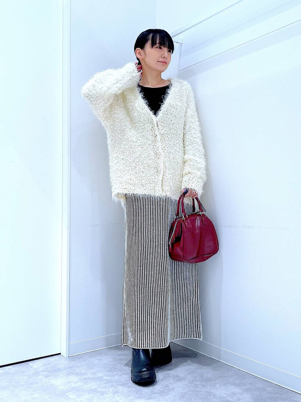 ブラック系のブーツ、ベージュ系のスカート、ベージュ系のカーディガン/ボレロを着用したレディースの秋コーディネートの2枚目の写真