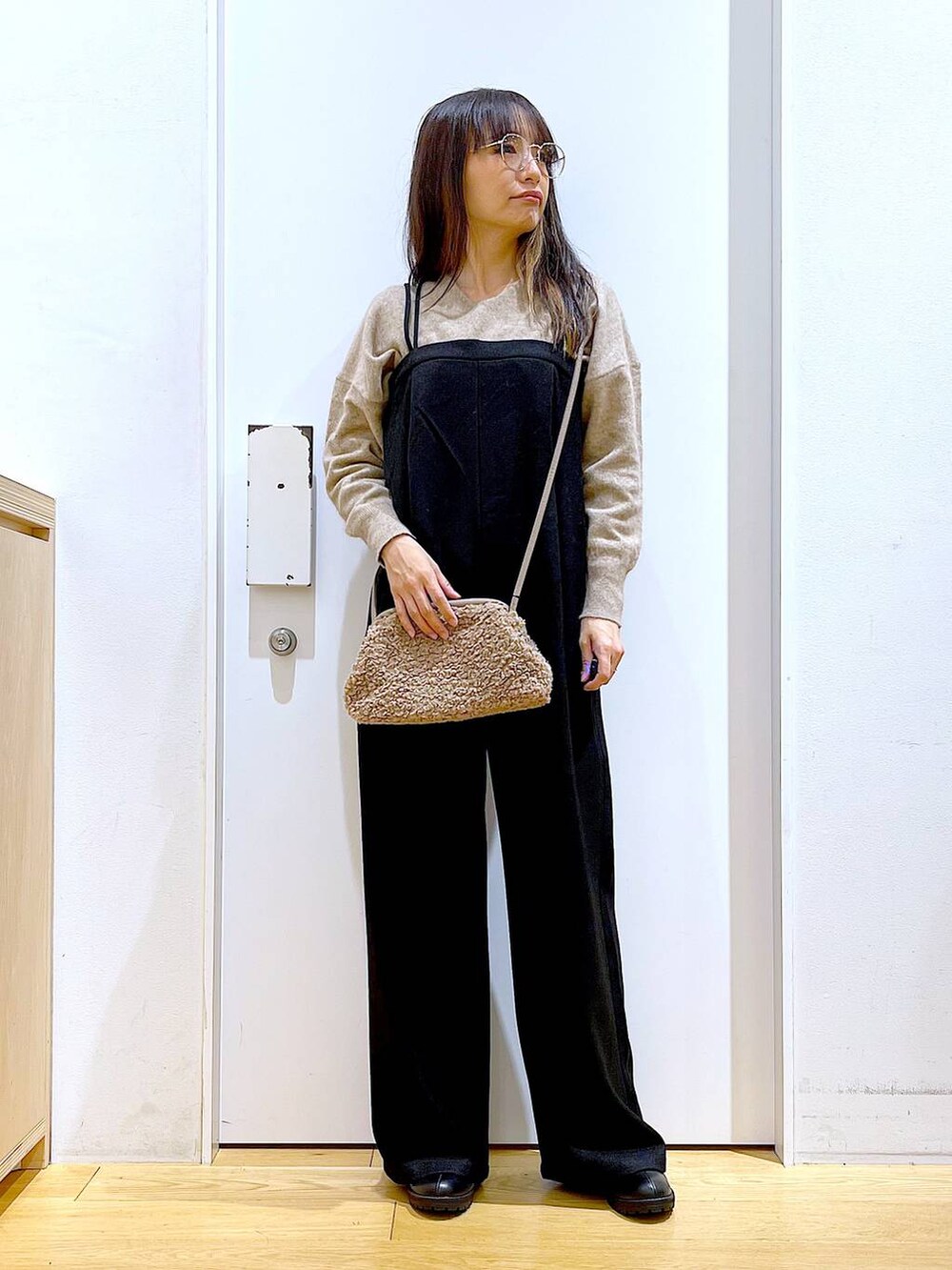 ベージュ系のニット/セーター、ブラック系のブーツ、ブラウン系のクラッチバッグを着用したレディースの冬コーディネートの2枚目の写真