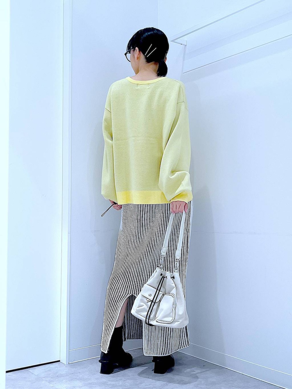 ホワイト系のショルダーバッグ、ベージュ系のスカート、ブラック系のブーツを着用したレディースの冬コーディネートの5枚目の写真