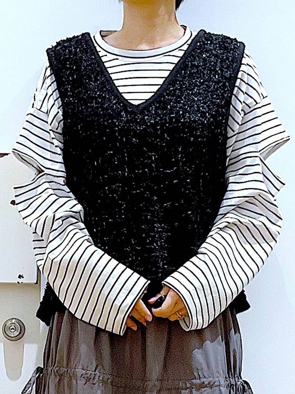 ブラック系のショルダーバッグ、ホワイト系のパンプス、グレー系のスカートを着用したレディースの秋コーディネートの7枚目の写真