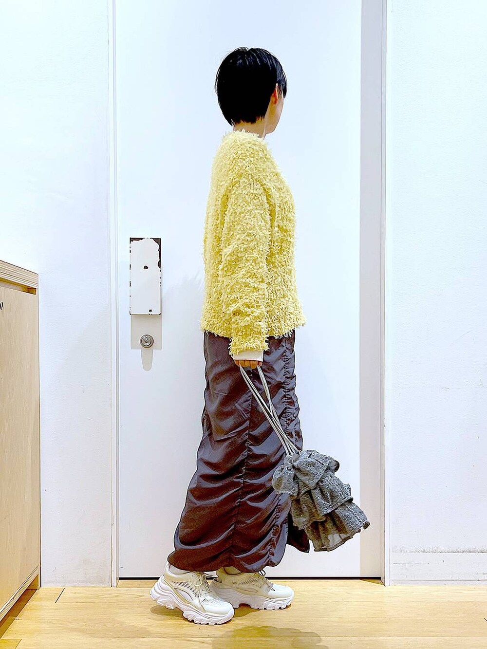 シルバー系のショルダーバッグ、グレー系のスカート、ホワイト系のスニーカーを着用したレディースの春コーディネートの4枚目の写真