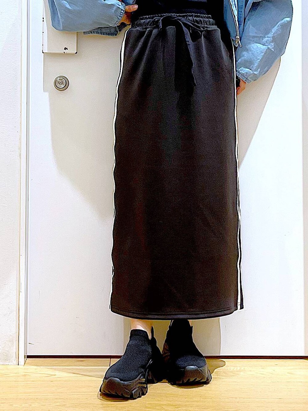 ブルー系のデニムジャケット、ブラック系のスカート、ブラック系のスニーカーを着用したレディースの春コーディネートの8枚目の写真