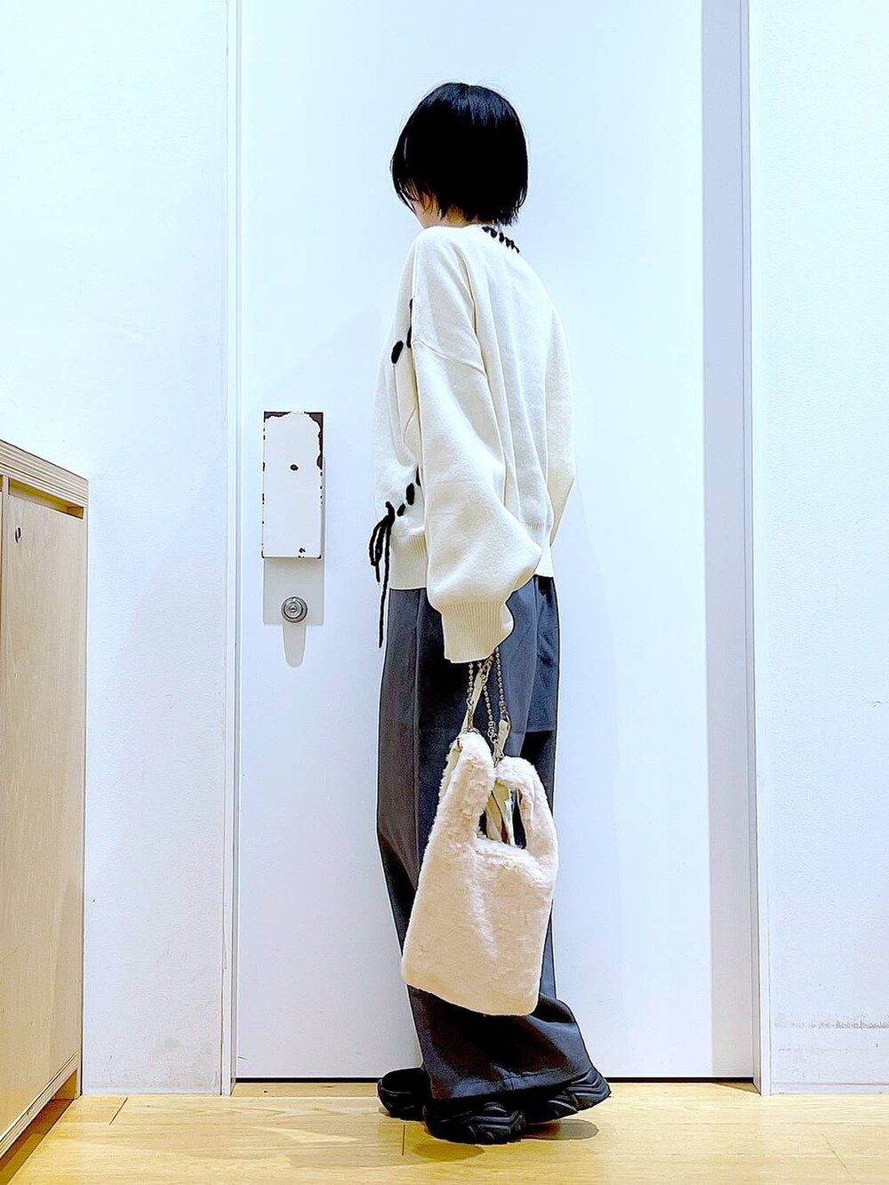 ホワイト系のショルダーバッグ、ブラック系のブーツ、グレー系のその他パンツを着用したレディースの冬コーディネートの3枚目の写真