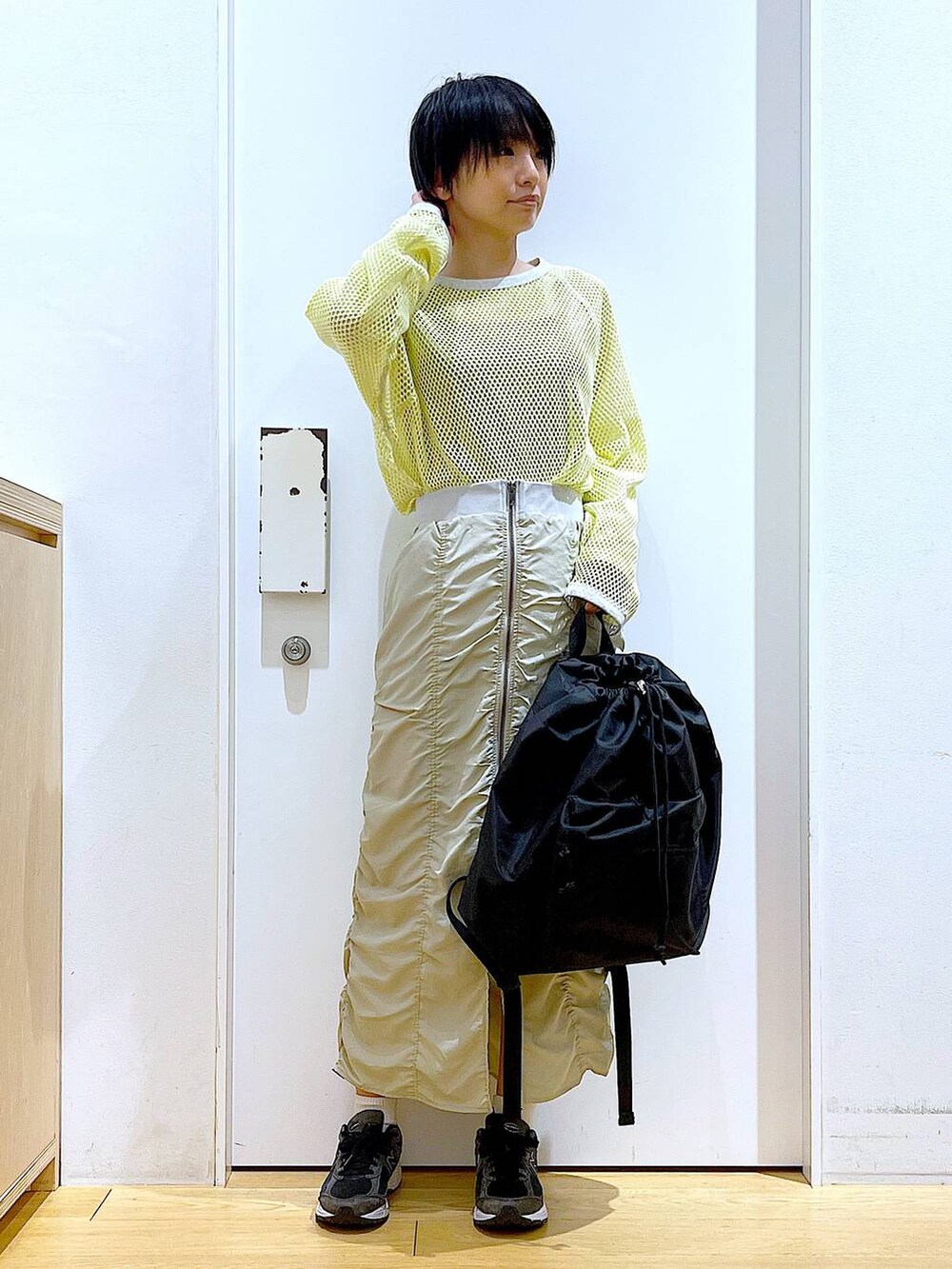 ベージュ系のスカート、ブラック系のバックパック/リュック、イエロー系のTシャツ/カットソーを着用したレディースの春コーディネートの2枚目の写真