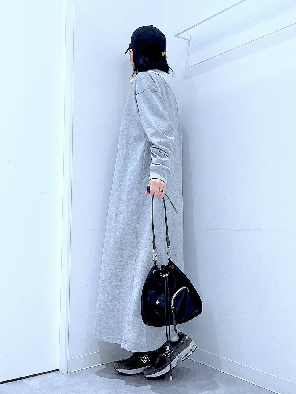 ブラック系のショルダーバッグ、グレー系のワンピース、ブラック系のキャップを着用したレディースの春コーディネートの3枚目の写真