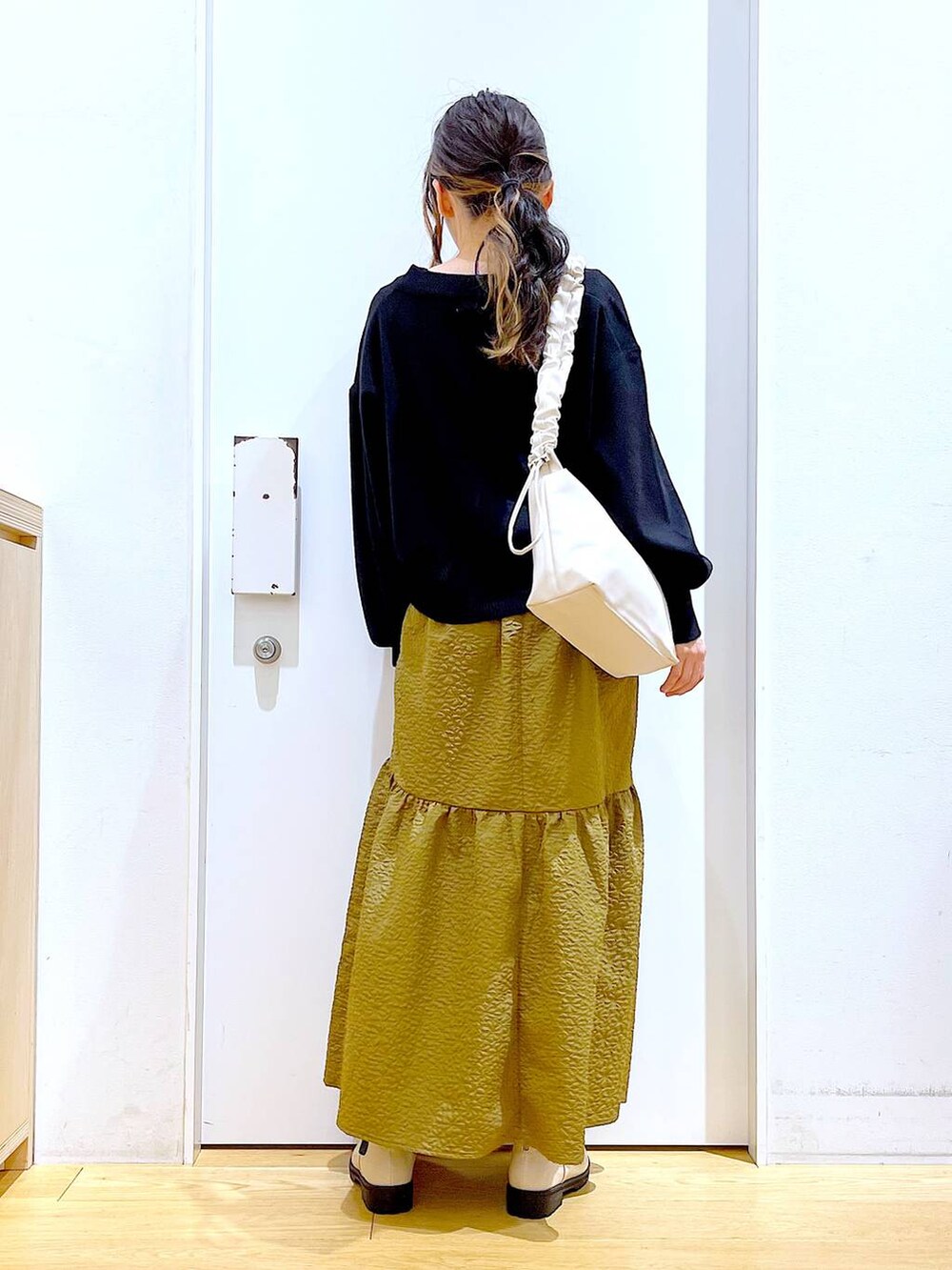 ホワイト系のショルダーバッグ、ベージュ系のブーツ、ブラック系のニット/セーターを着用したレディースの冬コーディネートの6枚目の写真